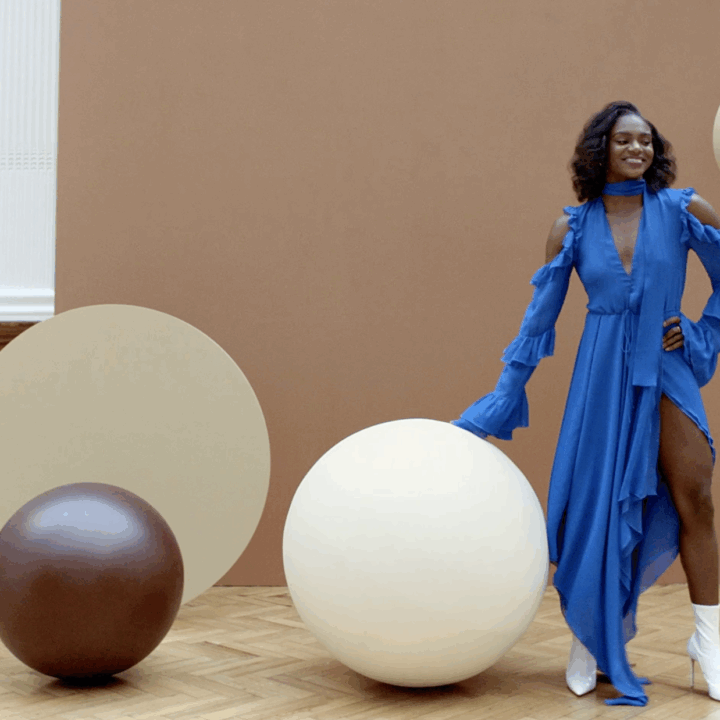 A woman in a blue dress surrounded by giant chocolate and white chocolate covered balls