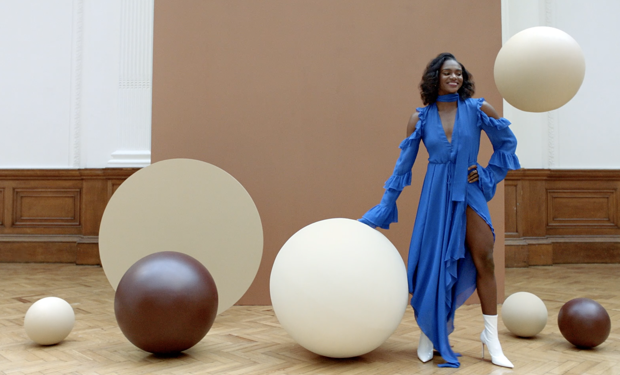 A woman in a blue dress surrounded by giant chocolate and white chocolate covered balls