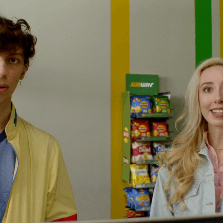 A couple in a Subway fast food restaurant with the Walkers crisps range displayed on a shelf behind them