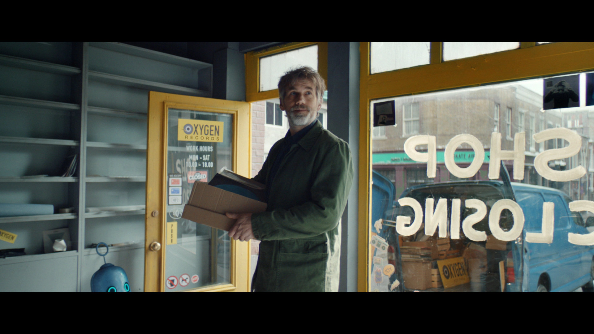 A man in a green shirt holding a box full of records