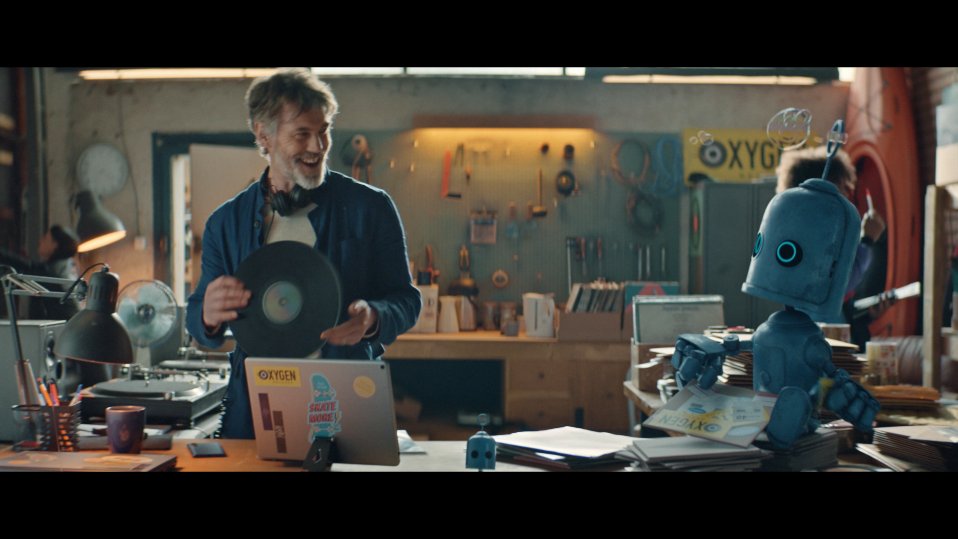 A man with a record in his hand laughing with a robot