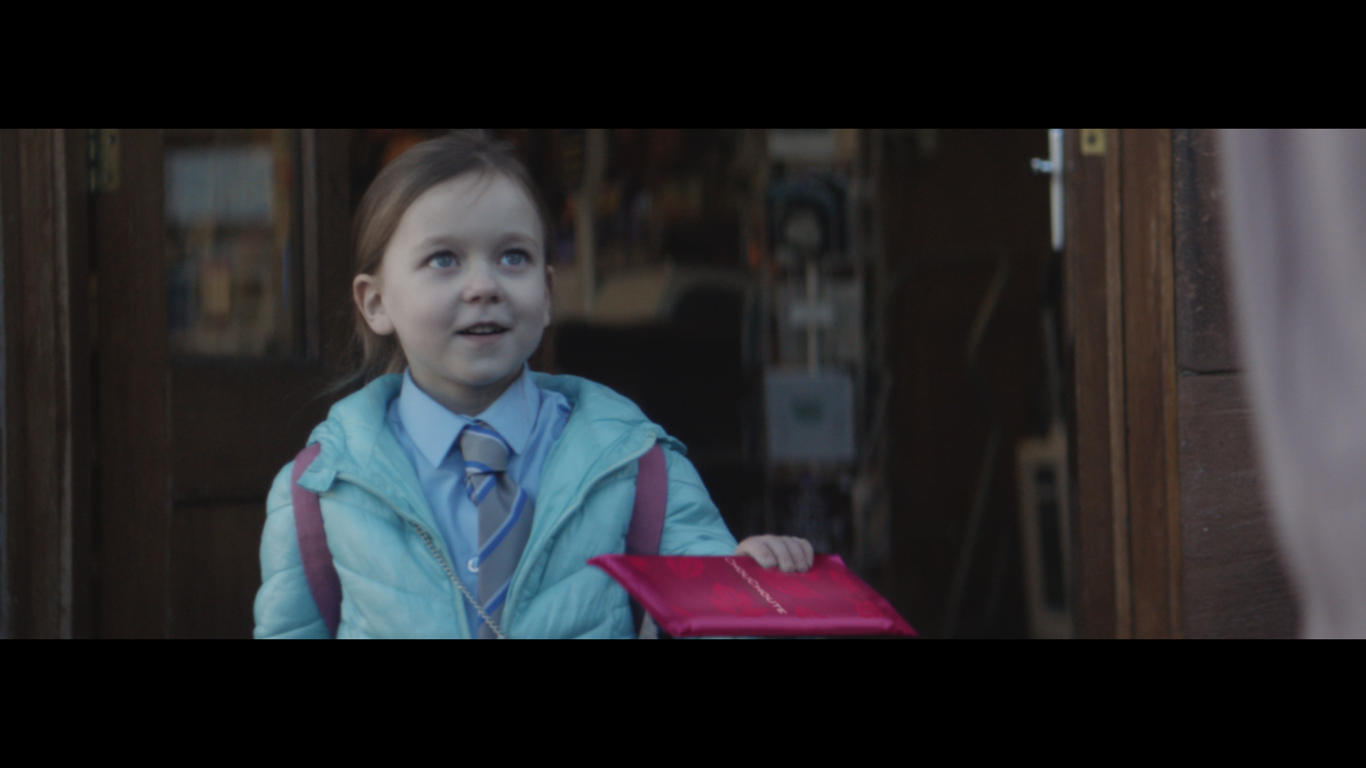 A little girl holding a pink packaged chocolate bar