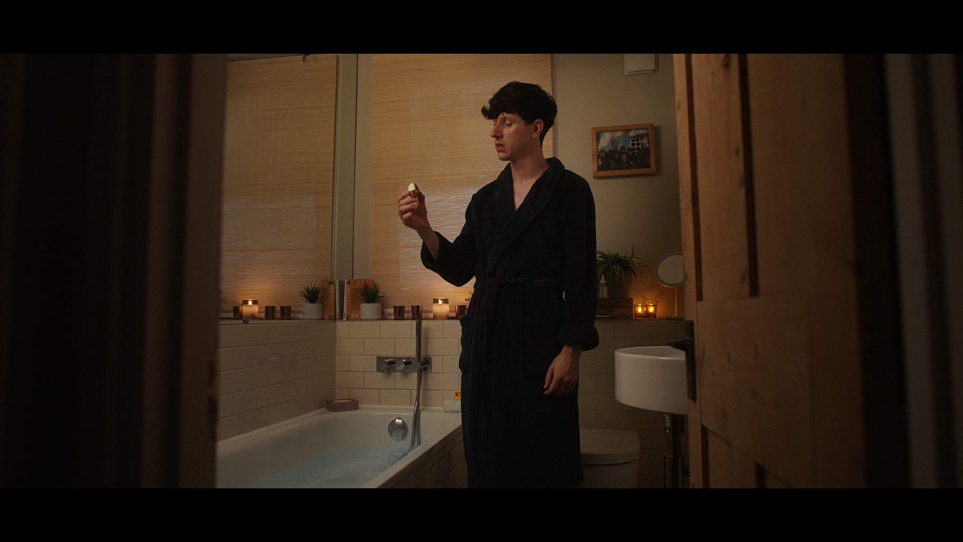 Man standing in front of a bath holding a creme egg chocolate.