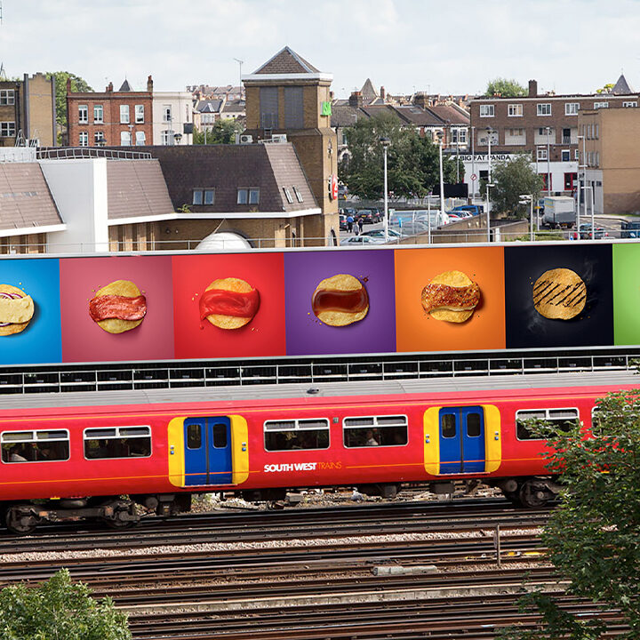Train passing by large billboard with Walkers Crisp advert