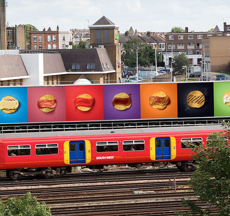 Train passing by large billboard with Walkers Crisp advert