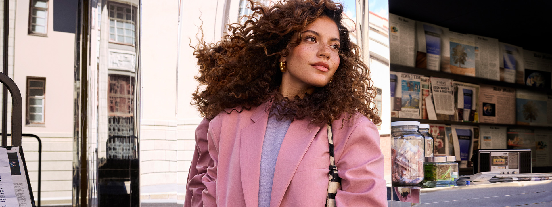 Woman standing in public with a newspaper for a John Frieda campaign.