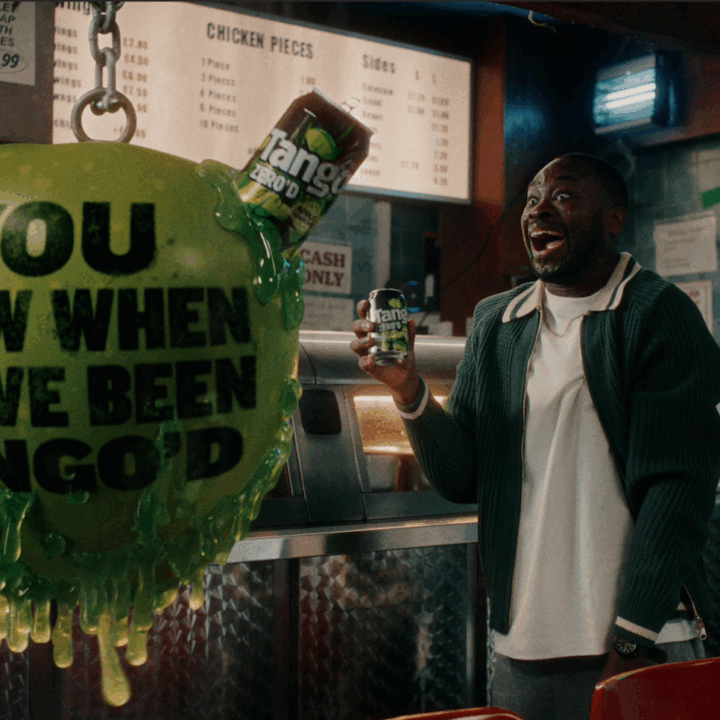 Happy man drinking Tango soft drink and a giant apple shaped wrecking ball