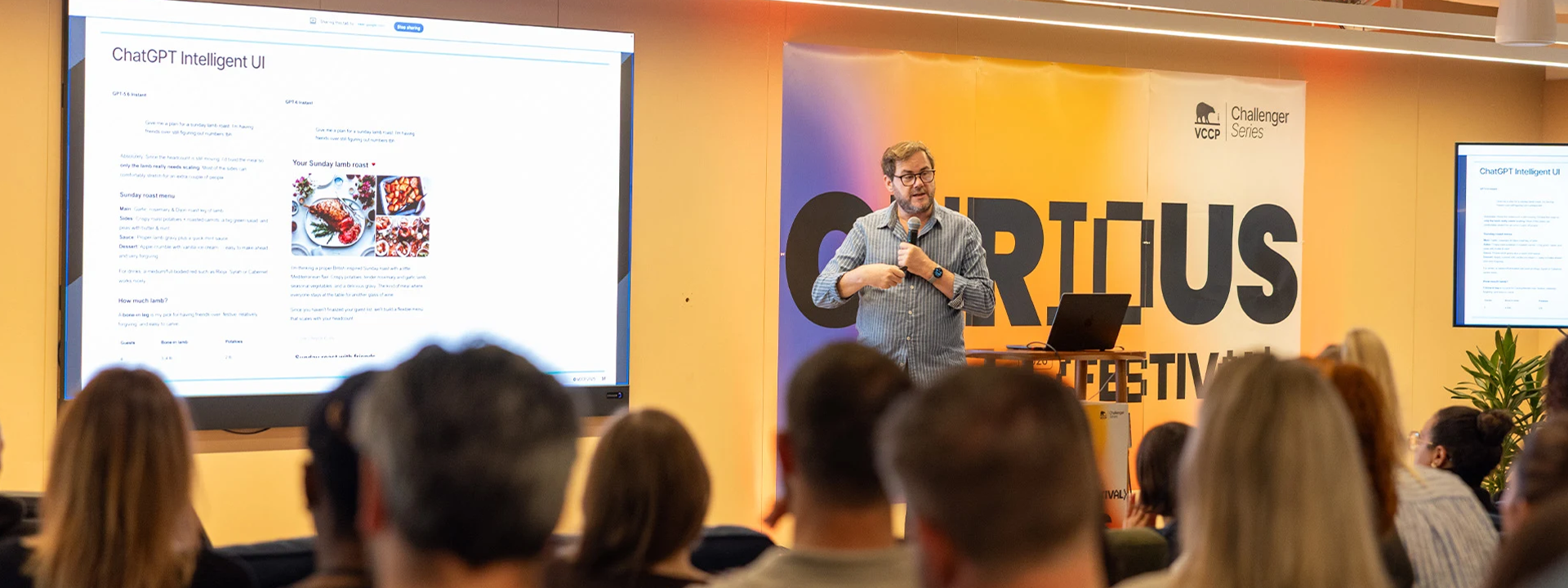 Peter Gasston presenting on stage at Curious Festival next to a screen and rows of people's head at the bottom of the image, displaying ChatGPT Intelligent UI.