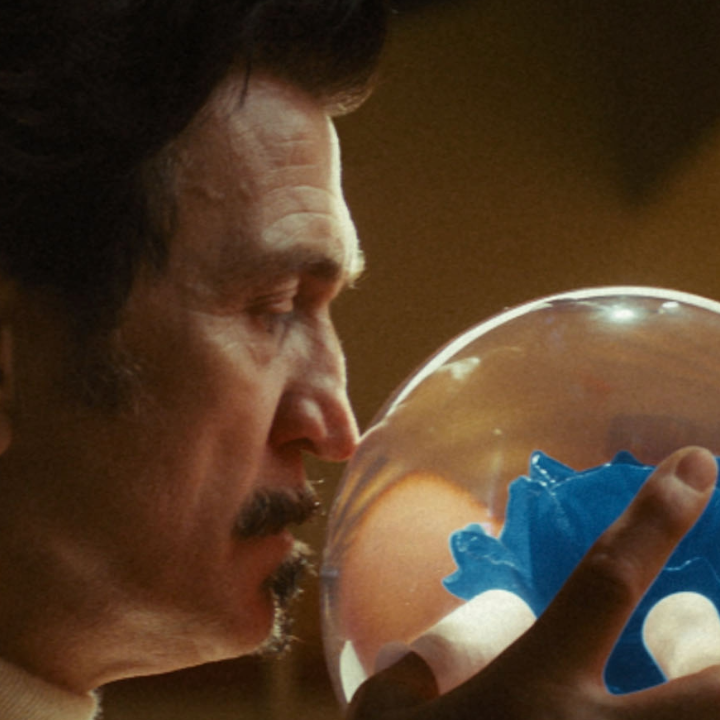 A man holding a transparent bowling ball with a blue flower in the centre