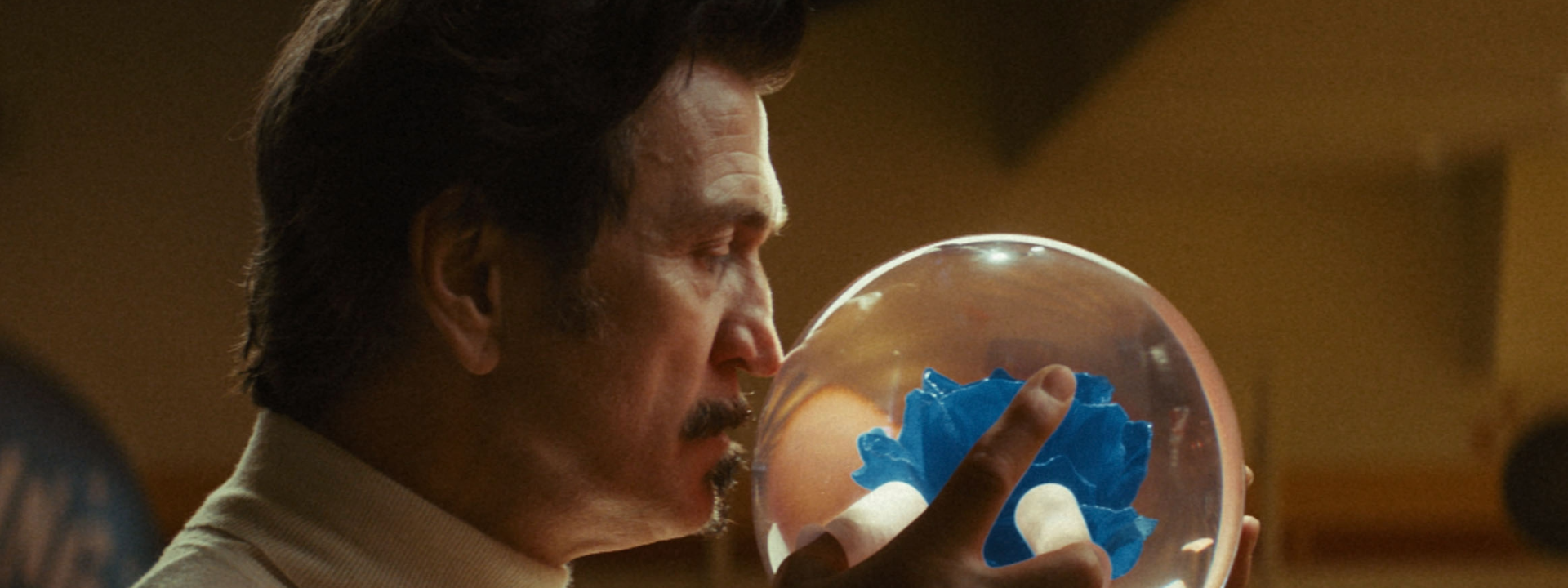 A man holding a transparent bowling ball with a blue flower in the centre
