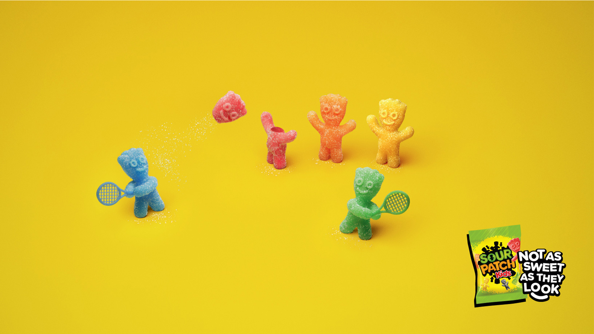 Sour Patch Kids advert showing blue and green gummy characters playing tennis with a red candy head with tagline Not as sweet as they look.