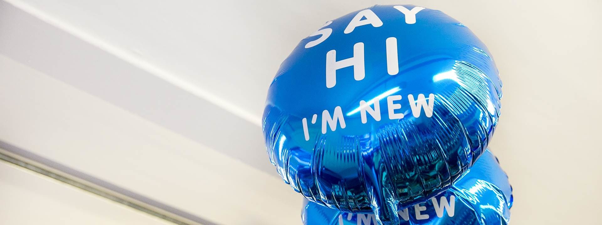 Blue balloon with white text. text reads: say hi I'm new