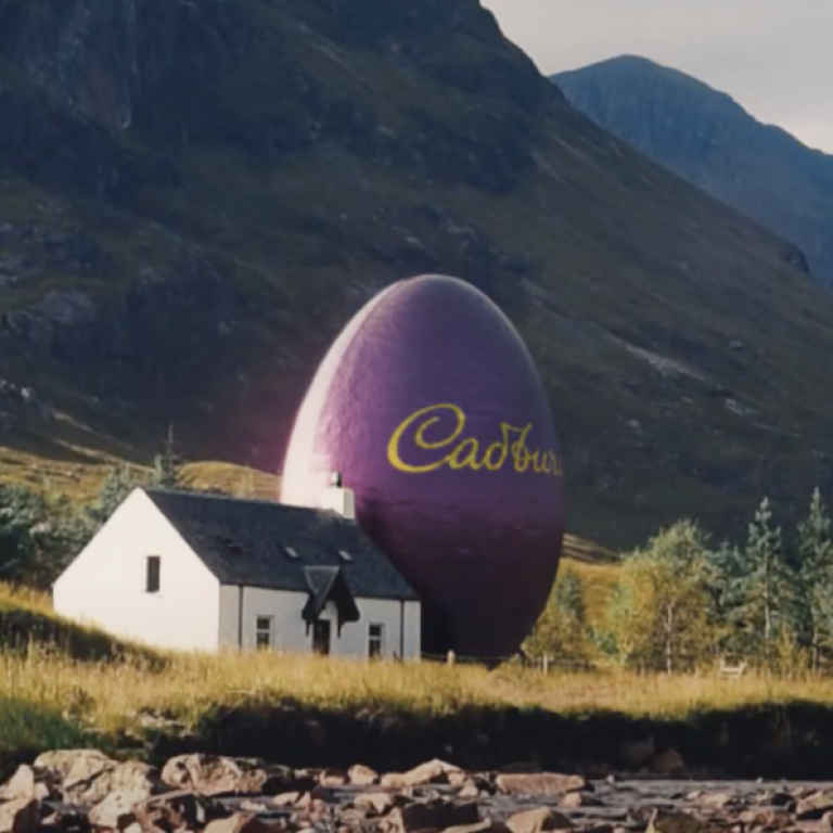 Countryside landscape scene with a giant purple Cadbury branded egg placed next to a house