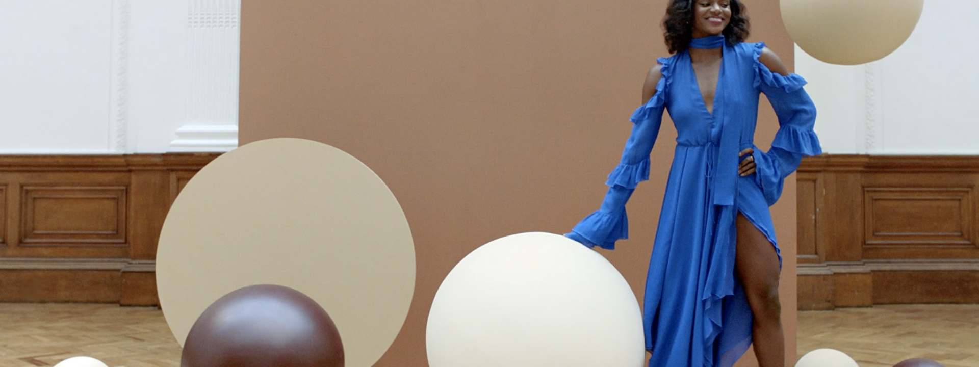 A woman in a blue dress surrounded by giant chocolate and white chocolate covered balls