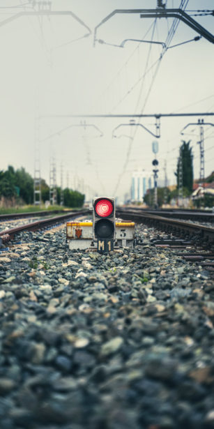 A red traffic light in the middle of some train tracks