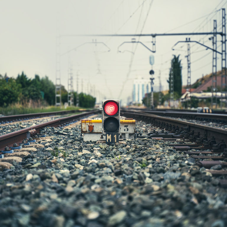 A red traffic light in the middle of some train tracks