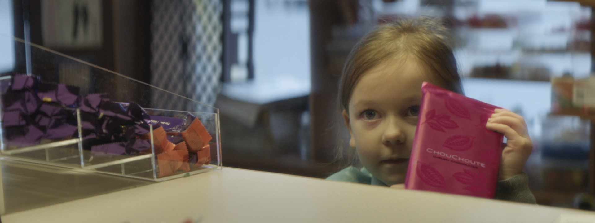 Closeup of a little girl holding a pink packaged chocolate bar