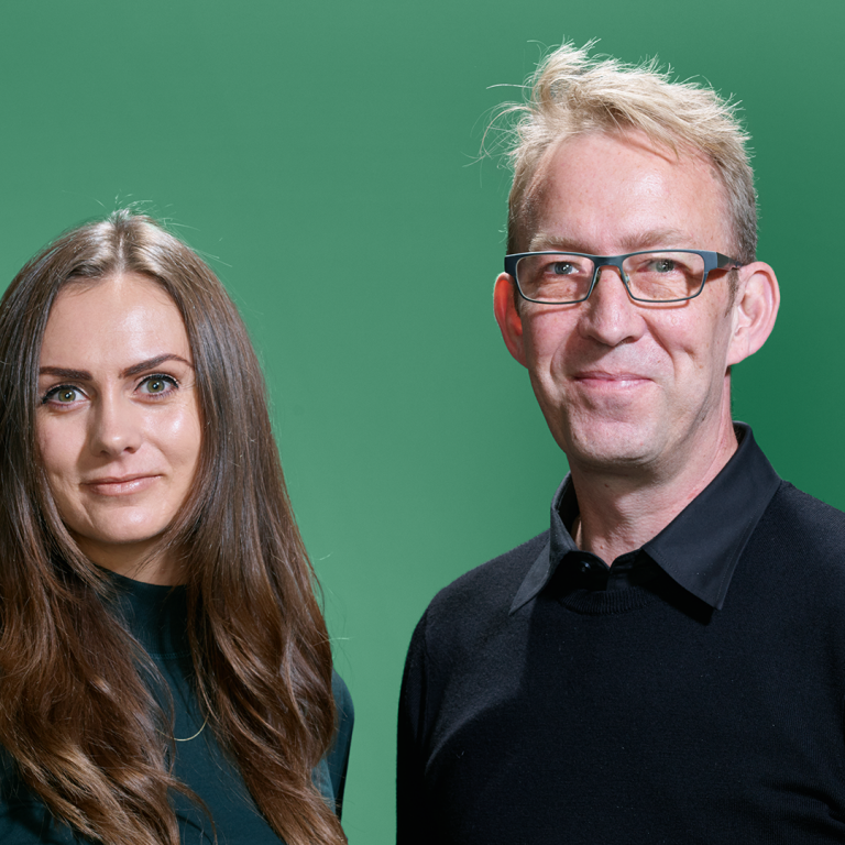 Ellen and Jakes standing together against a green background.