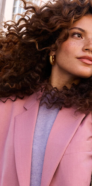 Woman standing in public with a newspaper for a John Frieda campaign.